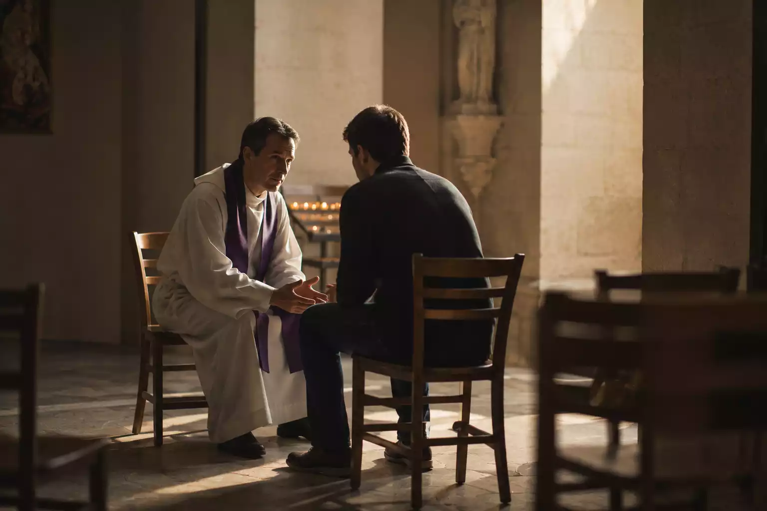 Un prêtre échange avec une personne dans une église lors d'un temps de confession